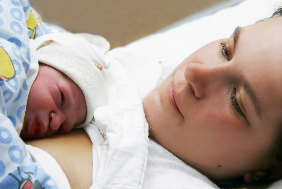 Woman looking at baby laying on her chest.